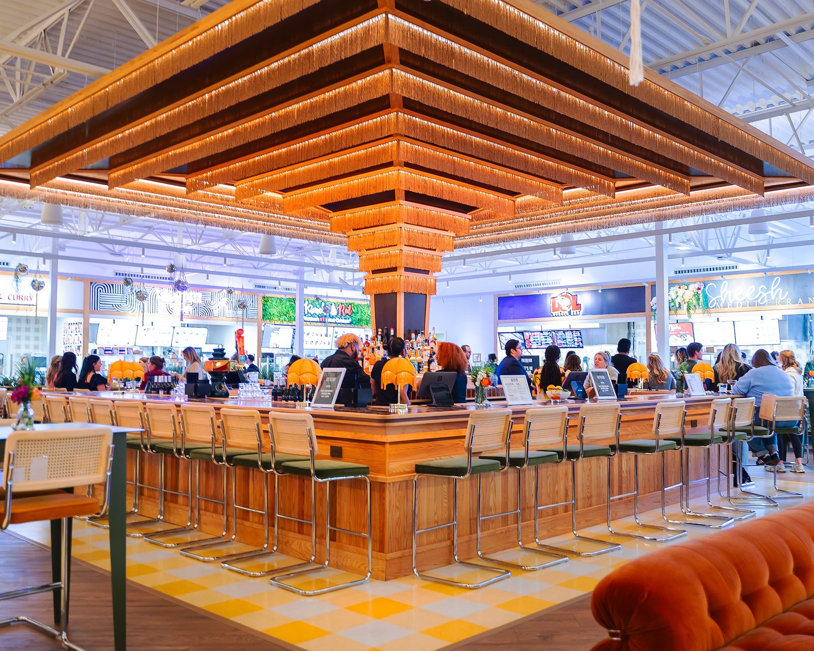 Wide view of a busy food hall bar under a wood-slat ceiling