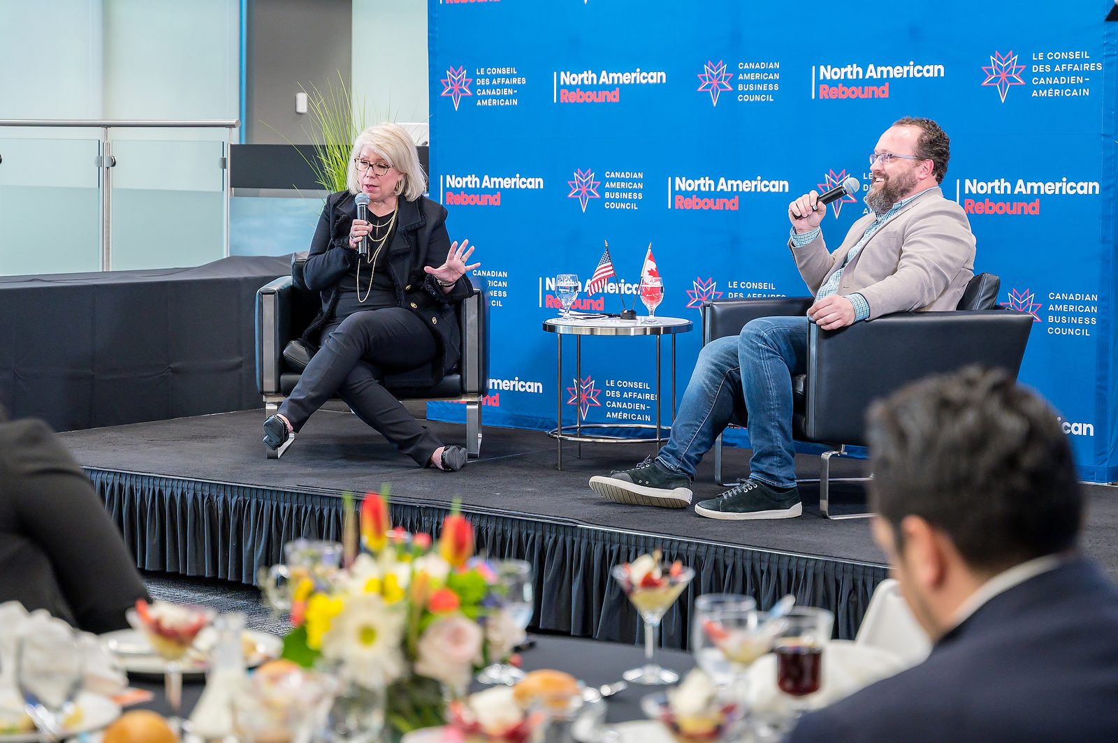 Two speakers in conversation on a conference stage