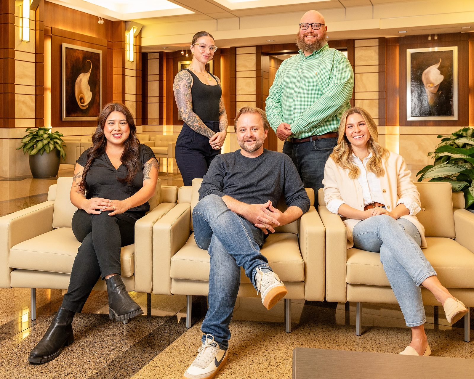 Five-person team seated on lobby sofas, group portrait